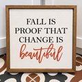 A square framed decorative sign with the text 'FALL IS PROOF THAT CHANGE IS beautiful' in black and orange lettering on a white background, set in a rustic brown wood frame.