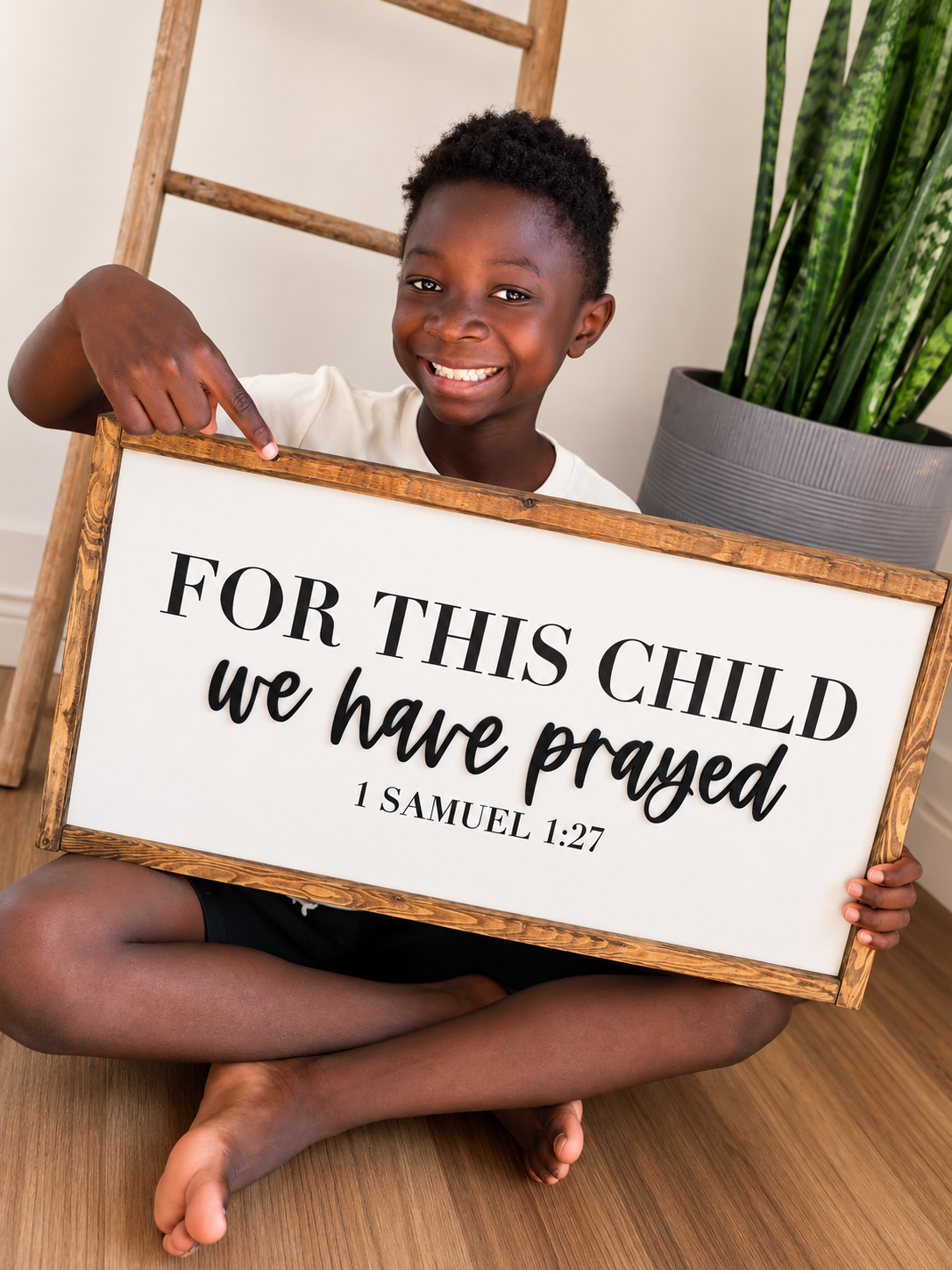 Child holding "For This Child We Have Prayed" framed Christian sign with 1 Samuel 1:27 Bible verse.
