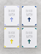 Four square wall art prints arranged in a 2x2 grid on a light gray textured background. Each print has the words 'ON YOUR BAPTISM' in black lettering above a simple cross, with different accent colors in the corners: light blue, dark blue, yellow, and teal.