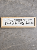 Framed wood sign featuring the quote "I Still Remember the Days I Prayed for the Things I Have Now" shown in a flat lay view.