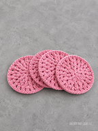 Four pink crocheted round coasters arranged in an overlapping fan shape on a textured gray concrete surface. The brand name 'ANCHOR AND LIGHT LLC' is visible in the bottom right corner.